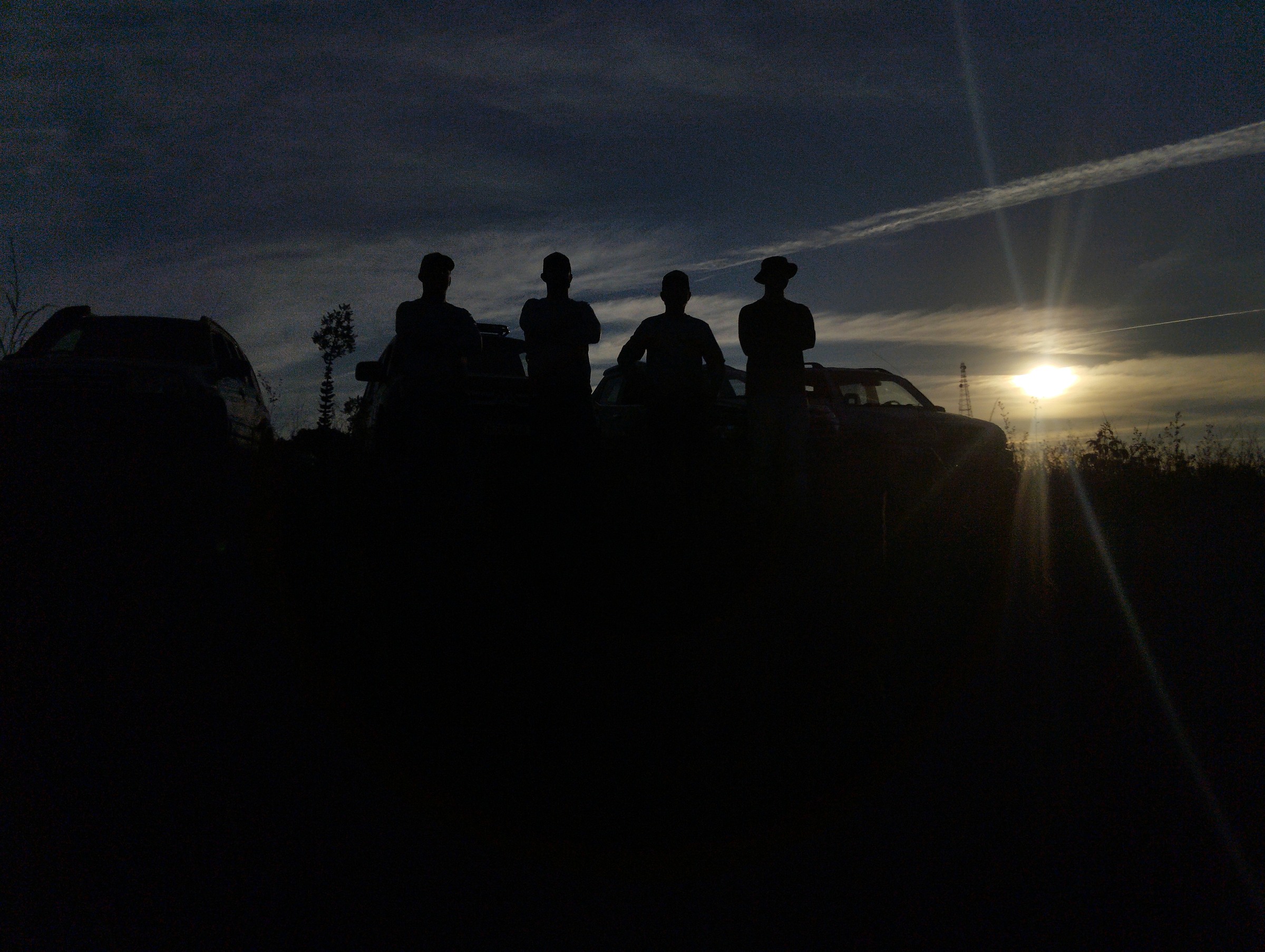 Grupo de participantes e veículos 4x4 ao pôr do sol